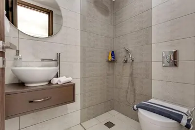 a bathroom with a sink and a toilet and a mirror at Villa Potami Angela by Villa Plus in Stílos