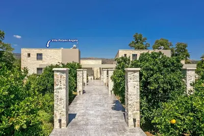 a stone pathway leading to a building with trees at Villa Potami Angela by Villa Plus in Stílos