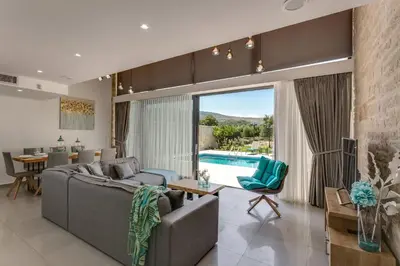 a living room with a couch and a table and a pool at Villa Potami Nikos by Villa Plus in Stílos