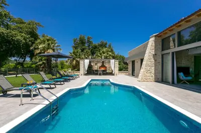 a swimming pool with chairs and a house at Villa Potami Nikos by Villa Plus in Stílos