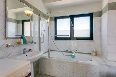 a bathroom with a tub and a sink and a mirror at Villa Katerina Pente by Villa Plus in Kalyves