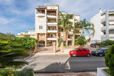 a red car parked in front of a building at Luxury Coastal Retreat, Mountain View Balcony with Palm Trees & Parking in Chania Town