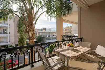 a balcony with a table and chairs and a palm tree at Luxury Coastal Retreat, Mountain View Balcony with Palm Trees & Parking in Chania Town