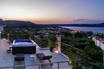 a balcony with a hot tub and chairs and the sunset at Villa Denise in Kalyves