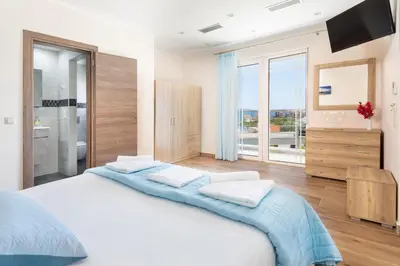 a white bedroom with a large bed and a large window at Villa Denise in Kalyves