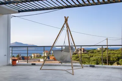 a swing on a patio with a view of the ocean at Villa Denise in Kalyves