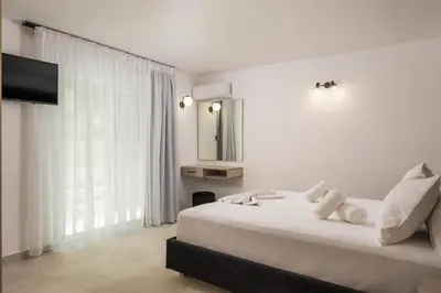 a white bedroom with a large bed and a mirror at Quarters Luxury Apts in Chania Town