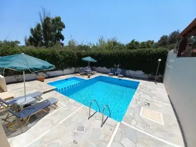 a swimming pool with two chairs and an umbrella at Casa Constans in Maleme