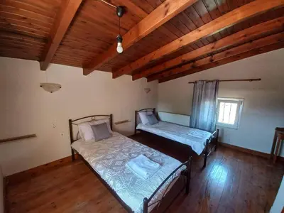 two beds in a room with wooden ceilings and wooden floors at Casa Constans in Maleme