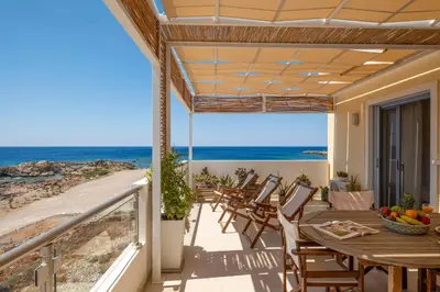 a patio with a table and chairs and the ocean at Aris Apartment in Palaiochóra