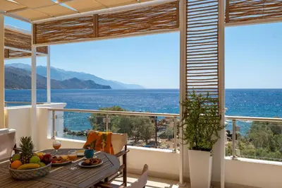 a dining room with a view of the ocean at Aris Apartment in Palaiochóra
