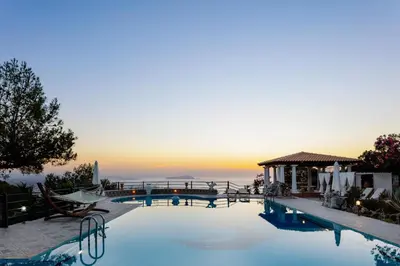 a pool with a view of the ocean at sunset at Villa Paparouna in Chania Town