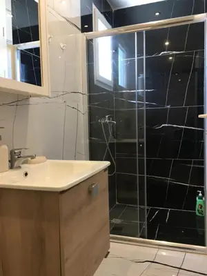 a bathroom with a sink and a shower with black tiles at Πολυτελές οροφοδιαμέρισμα για ονειρικές διακοπές! in Chania Town