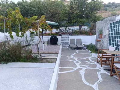 a patio with a table and chairs and a table and some trees at Jasmine Home by the Sea by 8essentially in Kalyves