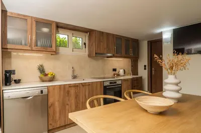 a kitchen with wooden cabinets and a table with a vase at Casa dei Sogni in Nerokoúros