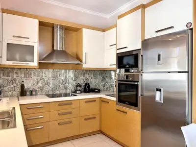 a kitchen with wooden cabinets and a stainless steel refrigerator at Central apartment in quiet neighborhood near sandy beach in Chania Town
