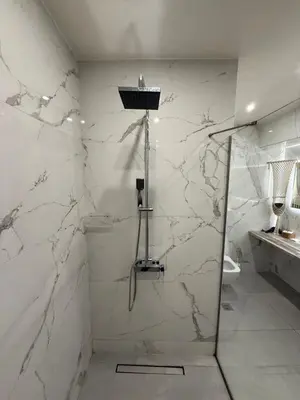 a bathroom with a shower with white marble walls at The house of JohnKou in Chania Town