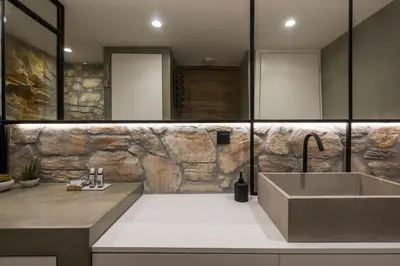 a bathroom with a sink and a stone wall at Skins Concept Boutique Apartment in Chania Town