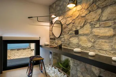 a bathroom with a stone wall and a mirror at Skins Concept Boutique Apartment in Chania Town