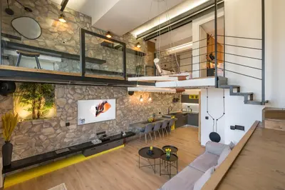an open living room and kitchen with a stone wall at Skins Concept Boutique Apartment in Chania Town