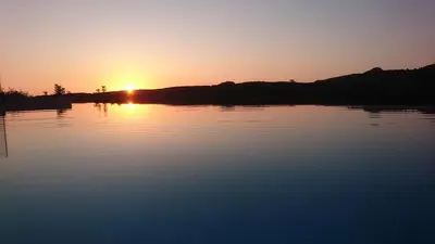 a sunset over a lake with the sun setting at Villa Olive Valley in Loutrákion
