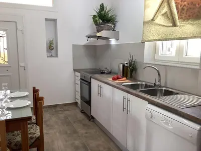 a kitchen with white cabinets and a sink and a table at Landro House in Kissamos
