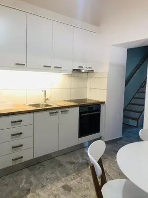 a kitchen with white cabinets and a sink and a table at Summer mood in Chania Town