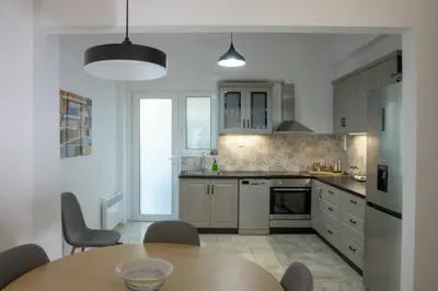 a kitchen with white cabinets and a table with chairs at Sfakion 6 apartment in Chania Town