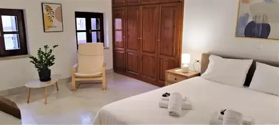 a bedroom with a large white bed and a chair at Canevaro Twins (South) in Chania Town