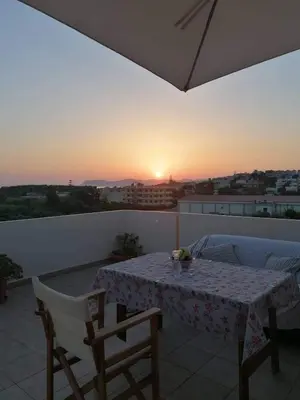 a table and chairs on a balcony with the sunset at Casa Ag.Apo in Daratso