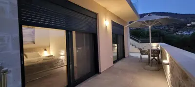 a balcony of a house with a table and an umbrella at Splendid Villas and Family Resort in Kalamitsi Amygdali