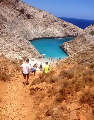 a group of people walking down a path to a beach at Hippie City Hostel in Chania Town