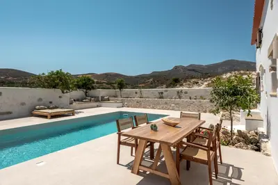 a patio with a table and chairs next to a pool at Villa Froudi in Kissamos