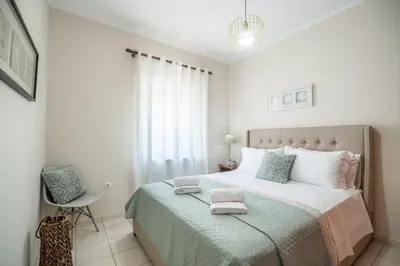 a white bedroom with a large bed and a chair at Ammoutsiani Cozy Apartment 1 by 8essentially in Chania Town