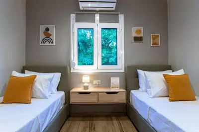 two beds in a room with a table and a window at Kares Dream House in Chania Town
