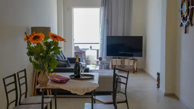 a living room with a table with a vase of flowers at KM Beach View apartment in Chania Town