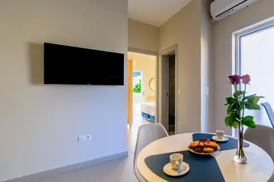 a living room with a table and a tv on a wall at Vakakis Family Luxury Studios 2 in Palaiochóra