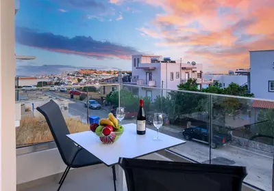 a table with a bottle of wine and a bowl of fruit at Vakakis Family Luxury Studios 2 in Palaiochóra