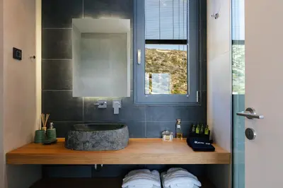 a bathroom with a stone sink and a window at Krystallon Villas in Palaiochóra
