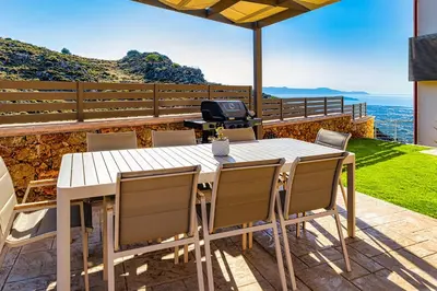 a table and chairs on a patio with a view of the ocean at Villa Lia Chania with private ecologic pool and amazing view! in Chania Town