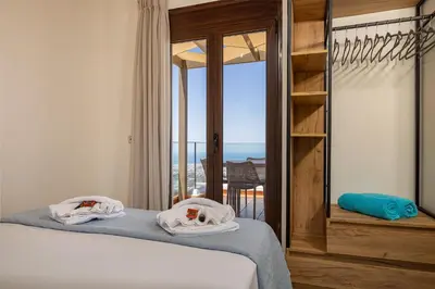a bedroom with a bed and a balcony with the ocean at Villa Lia Chania with private ecologic pool and amazing view! in Chania Town