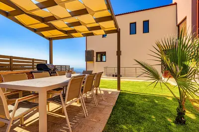 a table and chairs on a patio with a view of the ocean at Villa Lia Chania with private ecologic pool and amazing view! in Chania Town