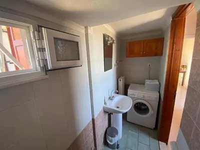 a small bathroom with a sink and a washing machine at Dusk Apartments with Stunning Mountain View in Chania Town