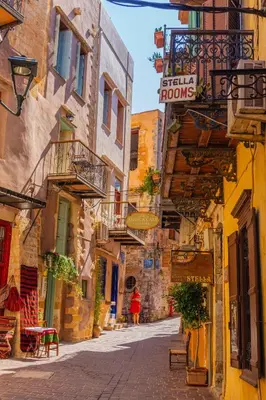 an alley in an old town with a woman walking down it at MYRTIA APARTMENT few steps from the sea in Chania Town