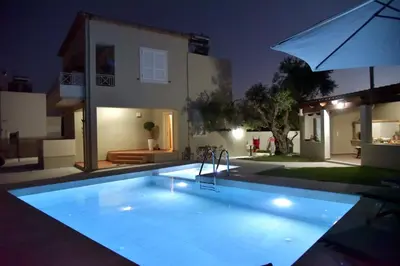 a swimming pool in front of a house at night at VILLA BLUE VEDERE in Gerani Chanion