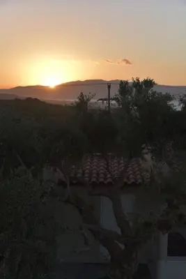 a sunset over a roof of a house with a tree at VILLA BLUE VEDERE in Gerani Chanion