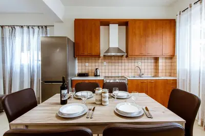 a kitchen with a wooden table with chairs and a refrigerator at OLIVE TREE in Galatás