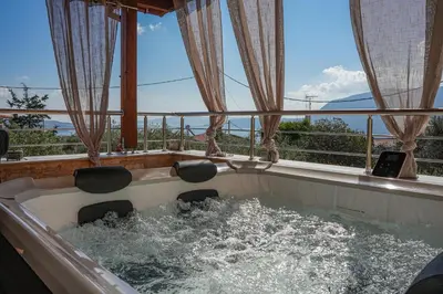 a bath tub filled with water next to a balcony at SundayMar Stone House in Chania Town