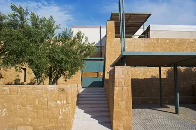 a building with a stone wall next to a sidewalk at Conte Marino Villas in Maleme