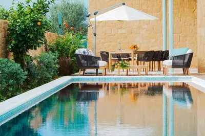 a pool with chairs and a table and an umbrella at Conte Marino Villas in Maleme